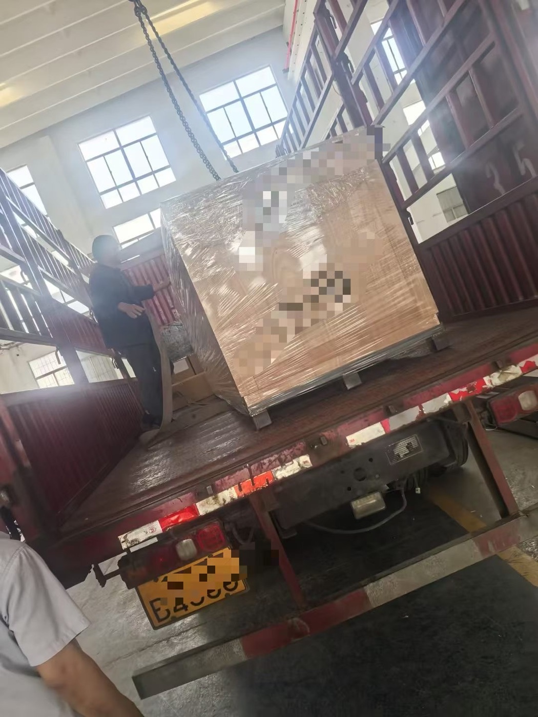 Crane lifting a heavy crated shipment onto a truck for transport to port